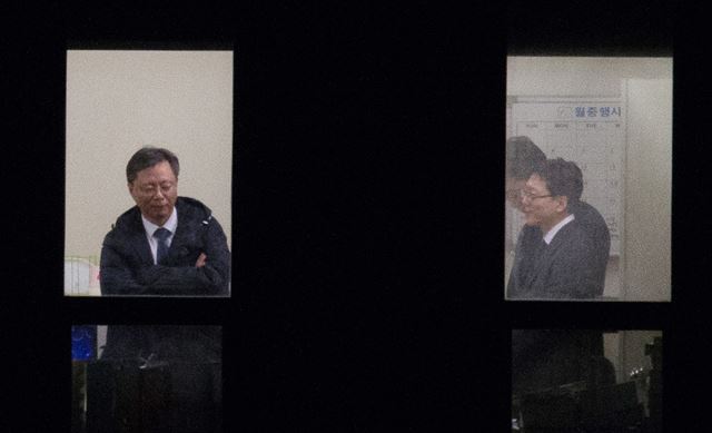 우병우(왼쪽) 전 수석이 서울 중앙지검에 소환돼 수사를 받던 6일 오후 11층 조사실에서 점퍼를 입고 팔짱을 낀 채 검찰직원들과 이야기하고 있다. 조선일보 제공