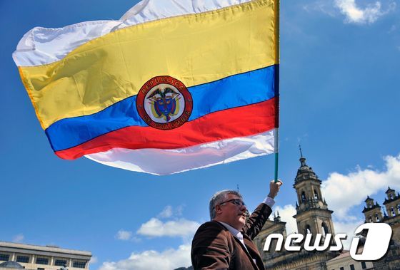 콜롬비아 정부와 최대 반군의 개정 평화협정이 하원에서 최종 통과된 30일(현지시간) 한 남성이 의회 밖에서 콜롬비아 국기를 들어 보이고 있다. © AFP=뉴스1