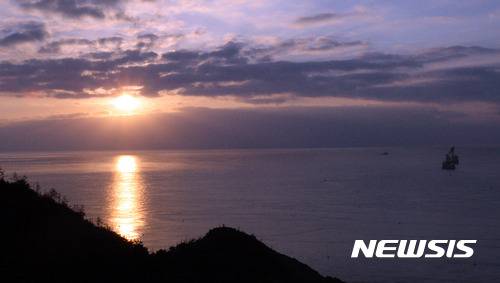 【진도=뉴시스】신대희 기자 = 정유년 새해 첫 날인 1일 오전 4·16 세월호 참사 가족협의회와 시민들이 전남 진도군 동거차도 감시초소에서 해맞이 행사를 열었다. 맹골수협 구름 사이로 해가 떠오르고 있는 가운데, 감시초소와 2.7km 떨어진 사고 해역에서 인양 업체인 상하이샐비지가 인양 사전 작업을 벌이고 있다. 2017.01.01. sdhdream@newsis.com