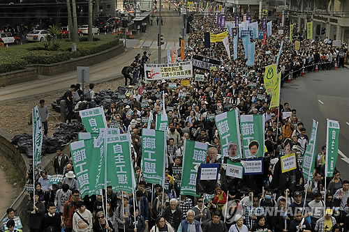 (AP=연합뉴스) 새해 첫날인 1일 홍콩 도심에서 시위대가 거리행진을 벌이고 있다. 수천 명의 시위대는 범민주파 입법회의원(국회의원격) 4명에 대해 제기한 사법심사 신청을 철회하라고 정부에 요구했다. 이들은 행정장관 보통선거 시행도 요구했다.