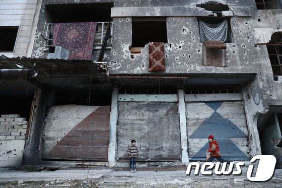 시리아 다마스쿠스 외곽 마을 두마의 파손된 건물 앞에서 어린이들이 뛰어놀고 있다. © AFP=뉴스1