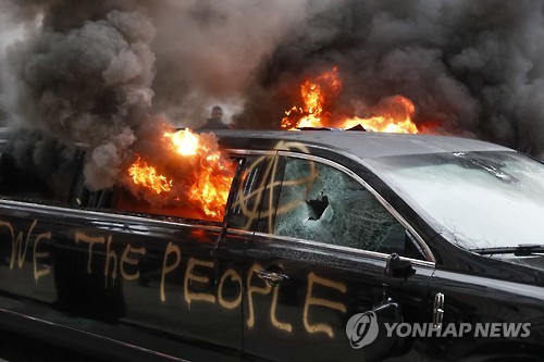 20일 워싱턴에서 반(反) 트럼프 시위 도중 주차된 차량이 불에 타고 있다 [AP=연합뉴스]
