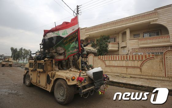 이라크 군인들이 22일(현지시간) 모술 동부 지역 탈환을 축하하며 이라크 깃발을 휘두르고 있다. © AFP=뉴스1