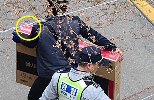 가전제품 상자를 든 설치기사가 지난 12일 오후 경찰의 안내를 받으며 박근혜 전 대통령의 서울 삼성동 사저로 들어가고 있다. LG전자의 HDTV였다. 뉴시스