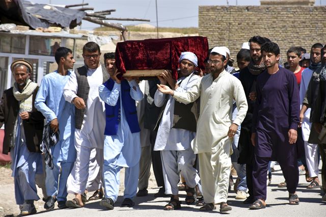 22일 아프가니스탄 마자르이샤리프 근처 사힌기지 앞에서 군으로부터 탈레반의 공격으로 희생당한 병사의 시신을 인계받은 유가족이 관을 든 채 이동하고 있다. 샤힌기지=AP 연합뉴스