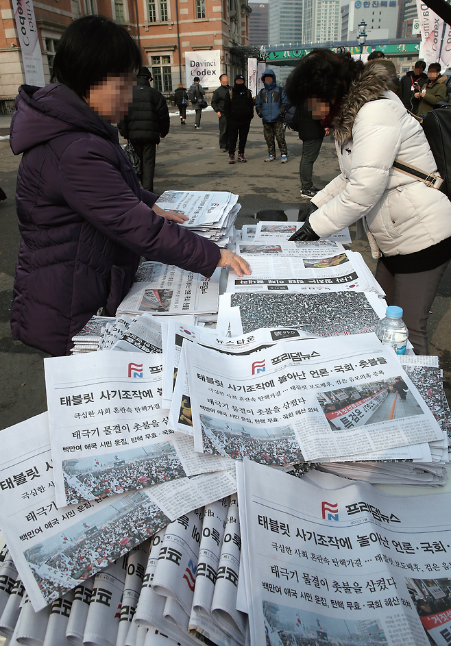 탄기국 회원들이 1월26일 서울역 광장에서 탄핵 반대 입장을 알리려고 제작한 신문을 배포하고 있다.© 연합뉴스