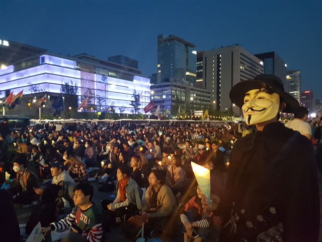 영화 '브이 포 벤데타' 복장을 착용한 회사원 김휘동(36)씨가 29일 오후 서울 광화문 광장에서 열린 마지막 촛불집회에서 촛불을 들고 있다. 정반석 기자
