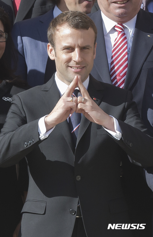 【파리=AP/뉴시스】에마뉘엘 마크롱 프랑스 대통령이 16일(현지시간) 파리 엘리제궁에서 열린 국제올림픽위원회(ICC) 관계자들과 만나 '파리 2024년 올림픽 유치'를 뜻하는 손가락 모양을 만들어 보이고 있다. 2017.5.17.