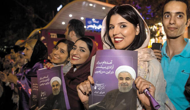 19일(현지 시각) 치러진 이란 대선에서 중도 개혁파인 하산 로하니 현 대통령이 57.1%의 득표율로 재선에 성공하자 로하니 지지자들이 테헤란 시내에서 로하니 얼굴이 들어간 포스터를 들고 승리의 미소를 짓고 있다. /신화 연합뉴스