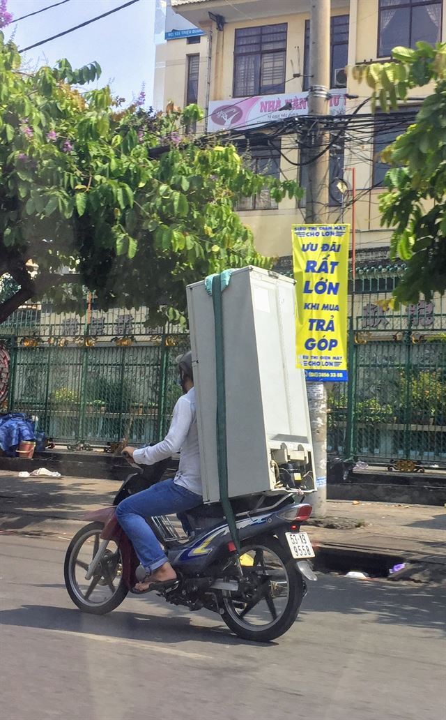 베트남에서는 오토바이에 못 싣는 게 없다. 한 운전자가 냉장고를 싣고 가고 있다.