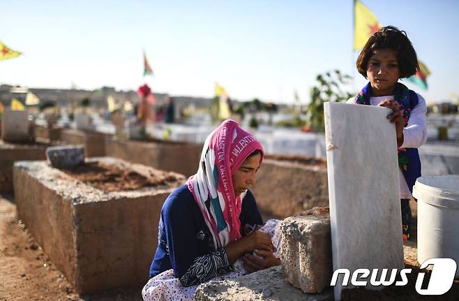 한 시리아 여성이 숨진 남편의 묘를 살피고 있다. © AFP=뉴스1