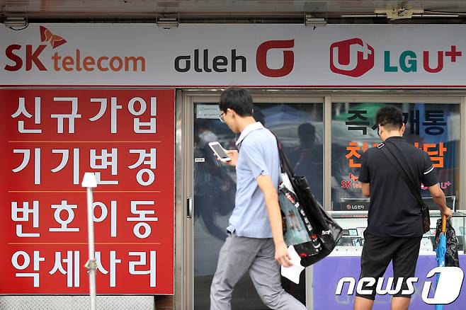 정부가 이동통신 3사에 25% 요금할인 상향 시행 방침을 밝힌 16일 오후 서울 용산구의 한 핸드폰 판매업소 앞을 시민들이 지나고 있다. © News1 임세영 기자
