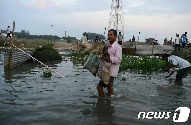계절풍인 몬순으로 인해 발생한 홍수로 인도·방글라데시·네팔 등지가 물에 잠겼다. 사진은 21일(현지시간) 물에 젖은 소지품을 운반하는 한 인도 남성의 모습. © AFP=뉴스1