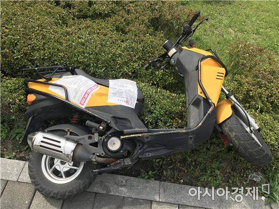 지난달 서울 용산구 한 길거리에 장기 방치된 소유주 미상 이륜차에 '무단방치 자동차 처리 안내문'이 붙어 있다. (사진=정준영 기자)