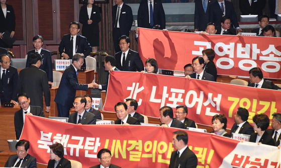 문재인 대통령이 1일 오전 국회 본회의장에서 2018년도 예산안 시정연설을 마친 뒤 현수막 시위를 벌이고 있는 한국당 의원들과 인사를 하며 퇴장하고 있다. [연합뉴스]