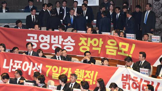 문재인 대통령이 1일 오전 국회 본회의장에서 2018년도 예산안 시정연설을 마친 뒤 현수막 시위를 벌이고 있는 한국당 의원들과 인사를 하며 퇴장하고 있다. [연합뉴스]