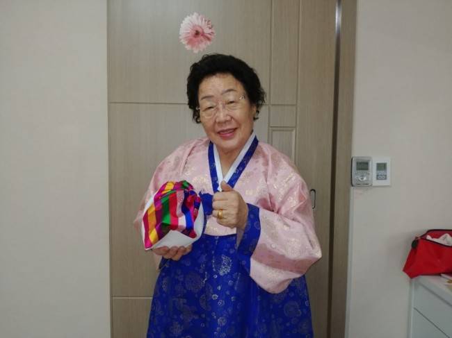 이용수 할머니가 청와대에서 받은 돌솥과 놋수저가 든 보자기를 들고 웃고 있다. [사진=정신대할머니와함께하는시민모임 제공]