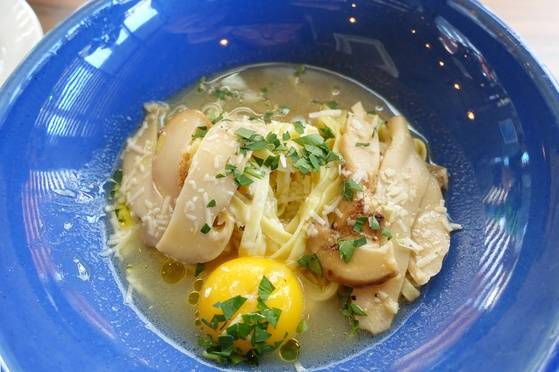 송이버섯과 백봉 오골계 초란 노른자를 올린 생면 탈리올리니. 국물이 있는 파스타다.