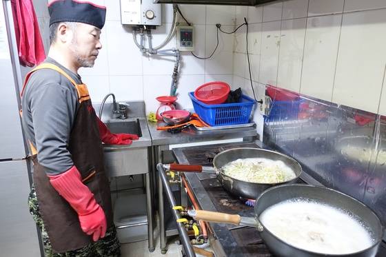 주인 홍탁근씨가 아귀수육을 만들면서 살을 삶다가 콩나물을 올린 다음 지켜보고 있다(왼쪽 냄비). 한쪽에서는 내가 먹을 아구탕이 끓고 있다.