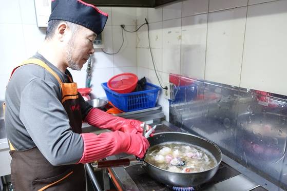 아귀수육을 조리하면서 끓는 밑국물에 살을 넣은 다음 가위로 위를 잘라 넣는 주인 홍탁근씨.