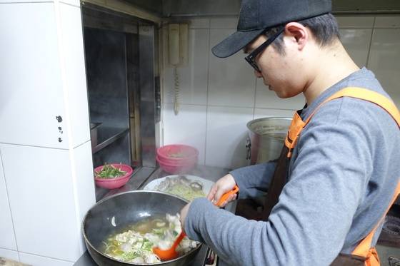아버지가 조리한 아구수육을 접시에 담고 있는 아들 홍주완씨. 음식점 명함에는 ‘대표’로 이름을 올렸다. 대학 조리학과를 나와 8년째 주방 수업을 하고 있다.