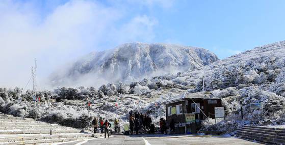19일 오전 제주 한라산 영실 코스를 찾은 등반객들이 첫눈이 내린 탐방로를 걷고 있다. [연합뉴스]