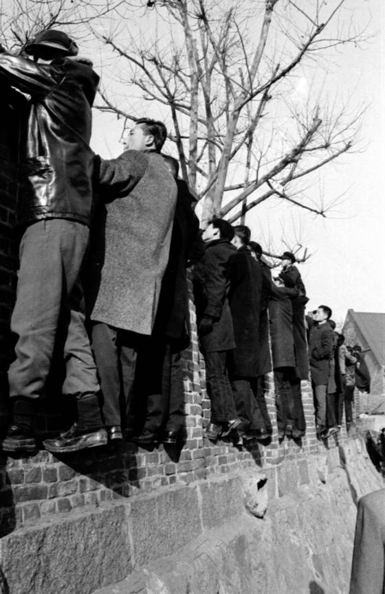 수험장에 들어간 자녀와 동생 등을 살펴보는 가족들. 담벼락에 올라 시험을 치르러 가는 수험생들을 바라보고 있다. [중앙포토]