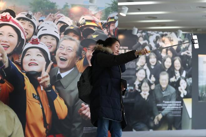 10일 서울 종로구 효자동 청와대 사랑채에서 열린 기획전시 '나라답게 정의롭게-대통령의 메시지로 보는 문재인 정부 214일'을 찾은 관람객이 전시된 사진을 배경으로 기념촬영을 하고 있다./사진=뉴스1