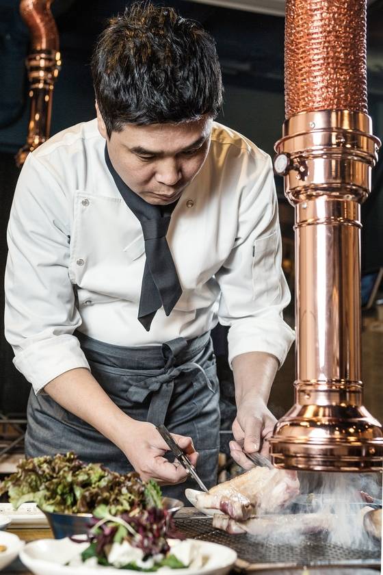 조리복을 갖춰 입고 표면을 익힌 오겹살을 자르는 국중성 대표. 점포 세 곳을 직영하다 보니 돌아다니느라 이런 모습을 보기는 쉽지 않다.