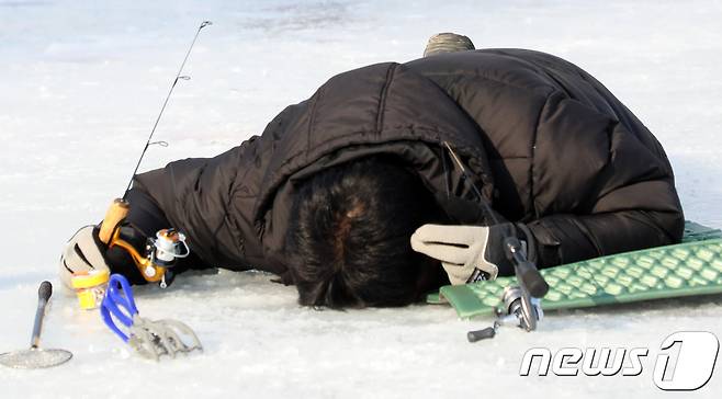 5일 강원 홍천군 홍천강변에서 제6회 홍천강 인삼송어 축제가 개막했다. 한 관광객이 얼름구멍을 들여다 보고 있다. 이번 축제는 오는 21일까지 계속되며 주요 프로그램은 얼음낚시, 가족텐트낚시, 인삼송어 맨손잡기 등이다. 2018.1.5/뉴스1 © News1 하중천 기자