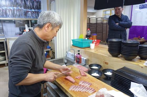 모둠 초덮밥을 만들려고 참치 뱃살 회를 뜨고 있는 주인 채성수씨. 초덮밥 메뉴를 만든 동생 성태씨가 바라보고 있다.