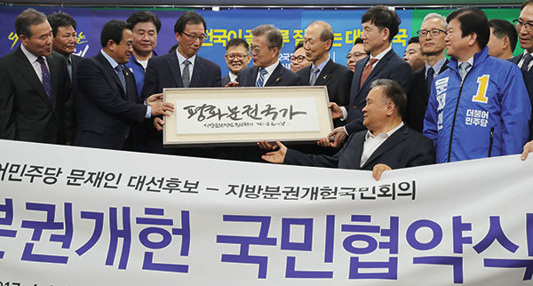 ⓒ연합뉴스 2017년 4월27일 문재인 더불어민주당 대선 후보(가운데)가 ‘평화분권국가’라 쓰인 액자를 건네받고 있다.