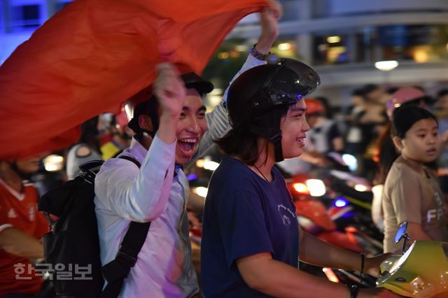 흥분의 도가니 베트남. 베트남이 아시아 4강에 오른 20일 저녁 베트남 국기를 든 한 커플이 호찌민 시내를 달리고 있다.