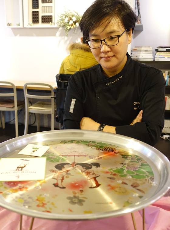 고영주 대표와 한국 출신 벨기에 입양인 만화가 융 에넹이 협업한 지난해 밸런타인데이 기획상품. 추억의 양은 상에 융이 그린 ‘꿀색 소년’ 캐릭터를 인쇄하고 분홍 보자기로 포장했다. 고 대표가 ’재미있고 공들인 기획인데 흥행은 실패했다“며 쓸쓸한 표정으로 상을 바라보고 있다.