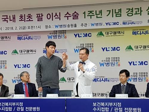 "제 팔입니다" (대구=연합뉴스) = 1년 전 이식수술을 받은 손진욱(왼쪽)씨 왼팔을 수술을 집도했던 우상현 W병원장이 함께 들어 보이고 있다. 2018.2.2  mshan@yna.co.kr