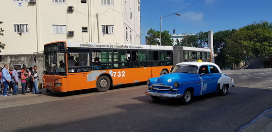 쿠바 아바나 대학 입구 버스 정류장. 버스 앞으로 올드카 택시가 지나고 있다.