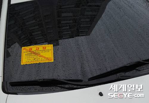불법주차로 경고 스티커가 붙은 차량. 아파트 경비원이 단지를 돌며 관리한다. 주의를 당부하는 정도다.