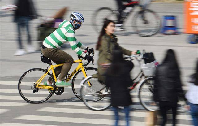 한 로드 바이크 이용자가 여의도지구 횡단보도를 지나며 앞선 대여용 자전거를 추월하고 있다.