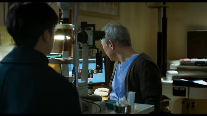 영화 <두개의 빛:릴루미노>에서 안과 의사가 황반변성 환자인 인수에게 증상을 설명하고 있다. 영화장면 캡처