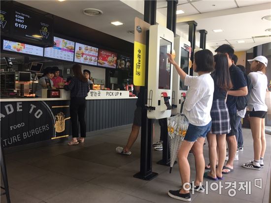 맥도날드의 무인결제기인 디지털 키오스크 앞에서 주문하는 사람들의 모습.