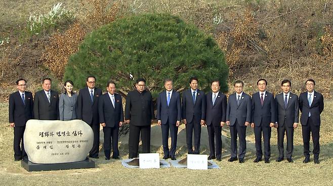 문재인 대통령과 김정은 북한 국무위원장이 27일 오후 판문점 군사분계선 인근 '소떼 길'에서 평화와 번영을 기원하는 소나무 공동식수를 마친 뒤 주요 참석자들과 기념촬영을 하고 있다. [연합뉴스 TV ]