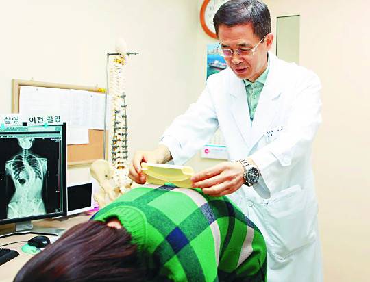 고려대 구로병원 서승우 교수가 지난 25일 척추측만증 여부를 확인하기 위해 한 여학생의 상체를 숙이게 한 뒤 등의 높낮이를 측정하고 있다.