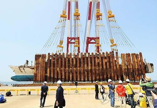 드디어 모습 드러낸 세월호 좌현 (목포=연합뉴스) 박철홍 기자 = 10일 오전 전남 목포시 목포신항에서 좌현을 바닥에 댄 채 거치 된 세월호가 세워지고 있다. 2018.5.10  pch80@yna.co.kr  (끝)