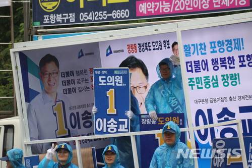 【포항=뉴시스】강진구 기자 = 6·13전국동시지방선거 경북도의회 포항시 제4선거구(장량동)에 출마한 더불어민주당 이송교 후보는 11일 오전 장량동 삼도W사거리에서 비가 오자 선거운동원들에게 우의를 입히고 차량 앞에 도열해 놓고 정작 자신은 차안에서 출근인사에 나서 눈살을 찌푸리게 했다.2018.06.11. dr.kang@newsis.com