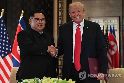 (싱가포르 AFP=연합뉴스) 역사적 첫 북미정상회담이 열린 12일(현지시간) 싱가포르 센토사 섬 카펠라호텔에서 미국 도널드 트럼프 대통령(오른쪽)과 북한 김정은 국무위원장이 공동합의문에 서명한 뒤 악수하고 있다.