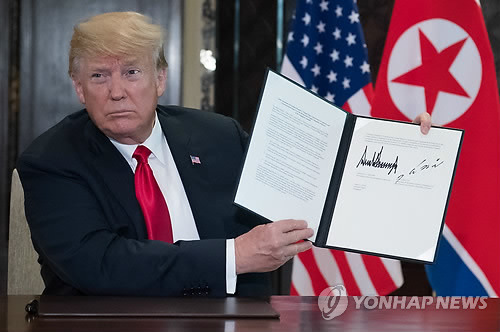 "한반도와 세계의 평화를 위해" (싱가포르 AFP=연합뉴스) 역사적 첫 북미정상회담이 열린 12일(현지시간) 싱가포르 센토사 섬 카펠라호텔에서 도널드 트럼프 미국 대통령이 자신과 김정은 북한 국무위원장이 서명한 공동합의문을 들어보이고 있다.       lkm@yna.co.kr