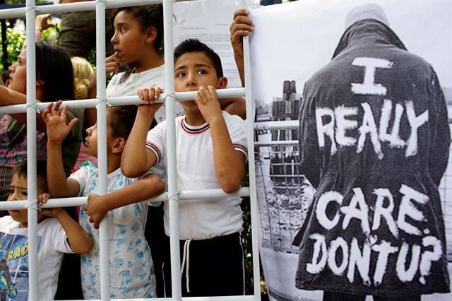 멕시코의 수도  멕시코 시티의 미국 대사관 앞에서 26일(현지시간)  미국의 반이민정책에 항의하며 철책을 세우고 시위를 하고 있는 어린이들 앞에 최근 논란이 되었던 멜라니아 여사가 입은 재킷을 패러디한 ' 난 정말 신경쓰여, 넌 안그래(I really care, Don't U?)'  사진이 부착되어 있다.   로이터 연합뉴스