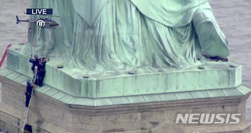 【뉴욕 = AP/뉴시스】 PIX11 텔리비전 방송의 헬기가 촬영한 7월 4일 독립기념일 날 자유의 여신상에 오른 여성의 체포 장면 .