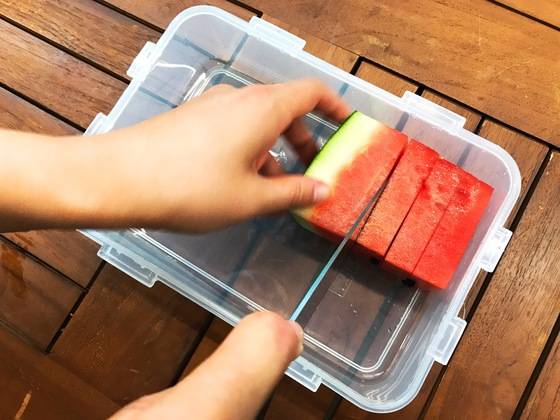 보관할 밀폐용기 그릇 높이에 맞춰 수박 조각을 넣고 식빵을 자르듯 칼로 툭툭 자른다.