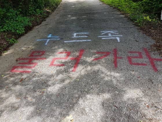 마을 주민들이 누드 펜션 운영에 강하게 반발했다. 트렉터로 오르는 길을 막거나(위 사진) 길에 항의의 문구를 써놓기도 했다(아래 사진). 지금은 펜션 운영을 더이상 하지 않고, 펜션 주인은 건물을 팔아 처분했다.[중앙포토]